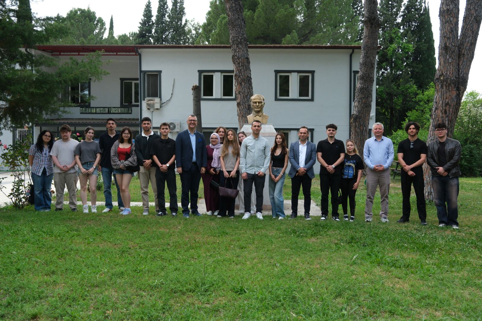 During the group photograph session held in the school grounds, students and participants are standing side by side in front of the building.
